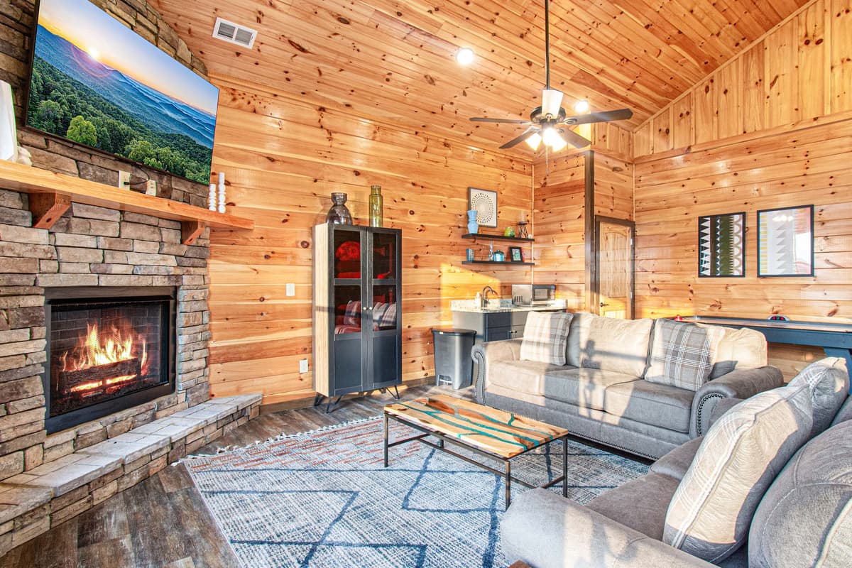 The upstairs living room offers an additional cozy space to relax, featuring comfortable sofa seating, a TV, and a warm fireplace.