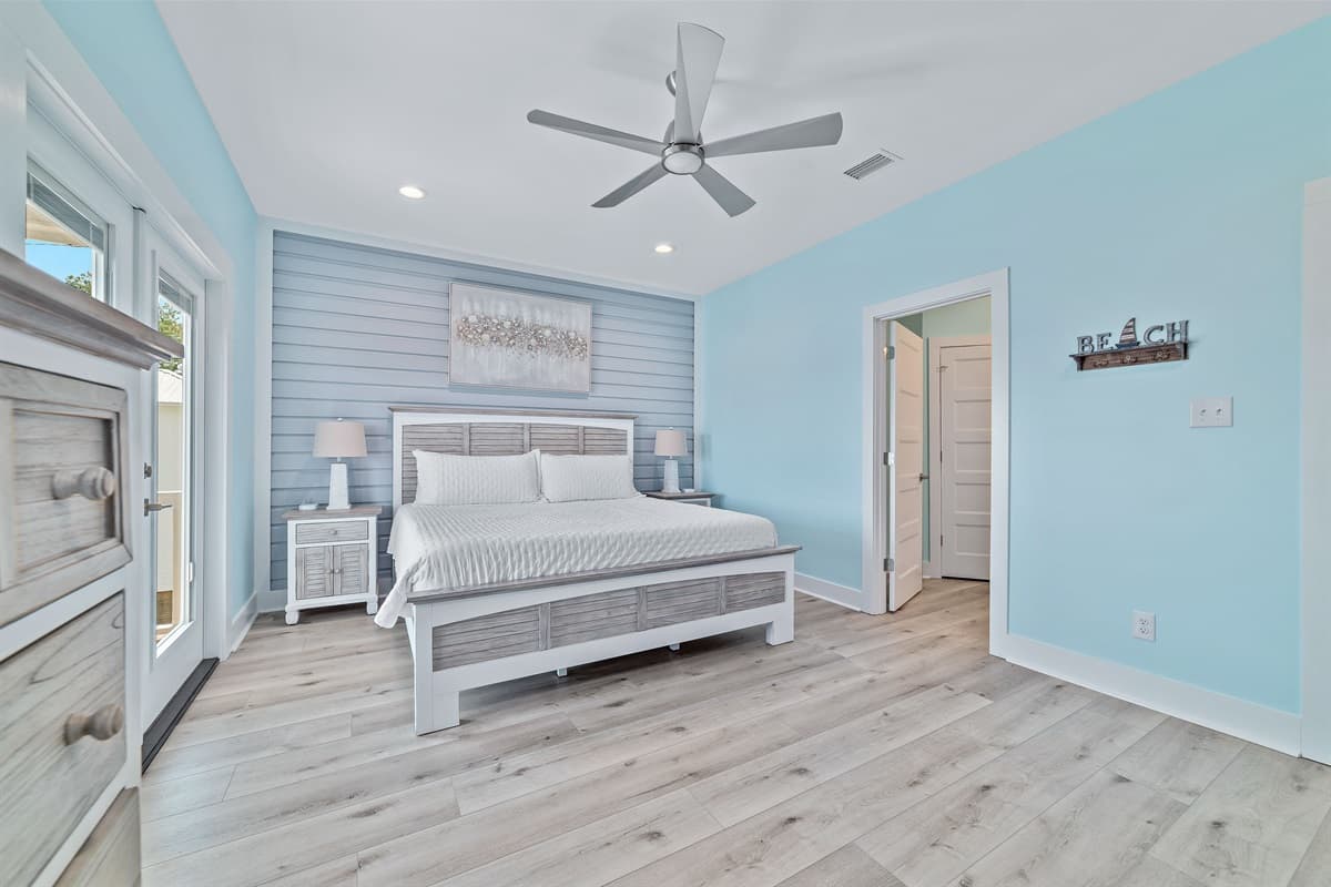 This bright and inviting bedroom features a comfortable king-sized bed with stylish light wood furniture and a striking shiplap accent wall.