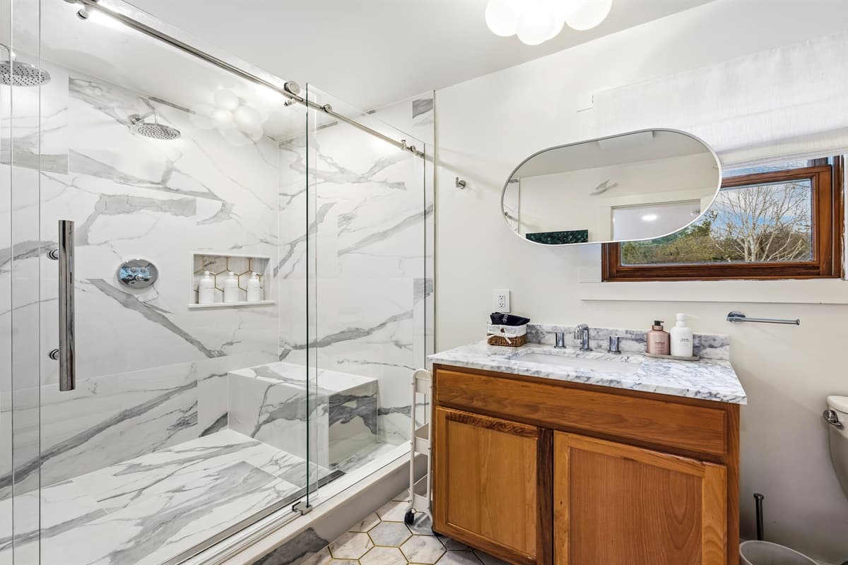 Both upstairs guest bedrooms share access to a spacious, modern bathroom featuring a large walk-in shower with double shower heads.