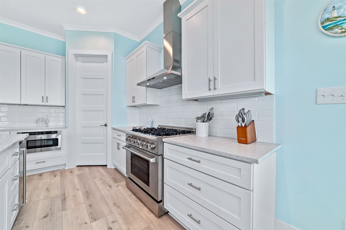 The modern kitchen is equipped with a gas range and stylish white cabinetry, perfect for culinary endeavors.