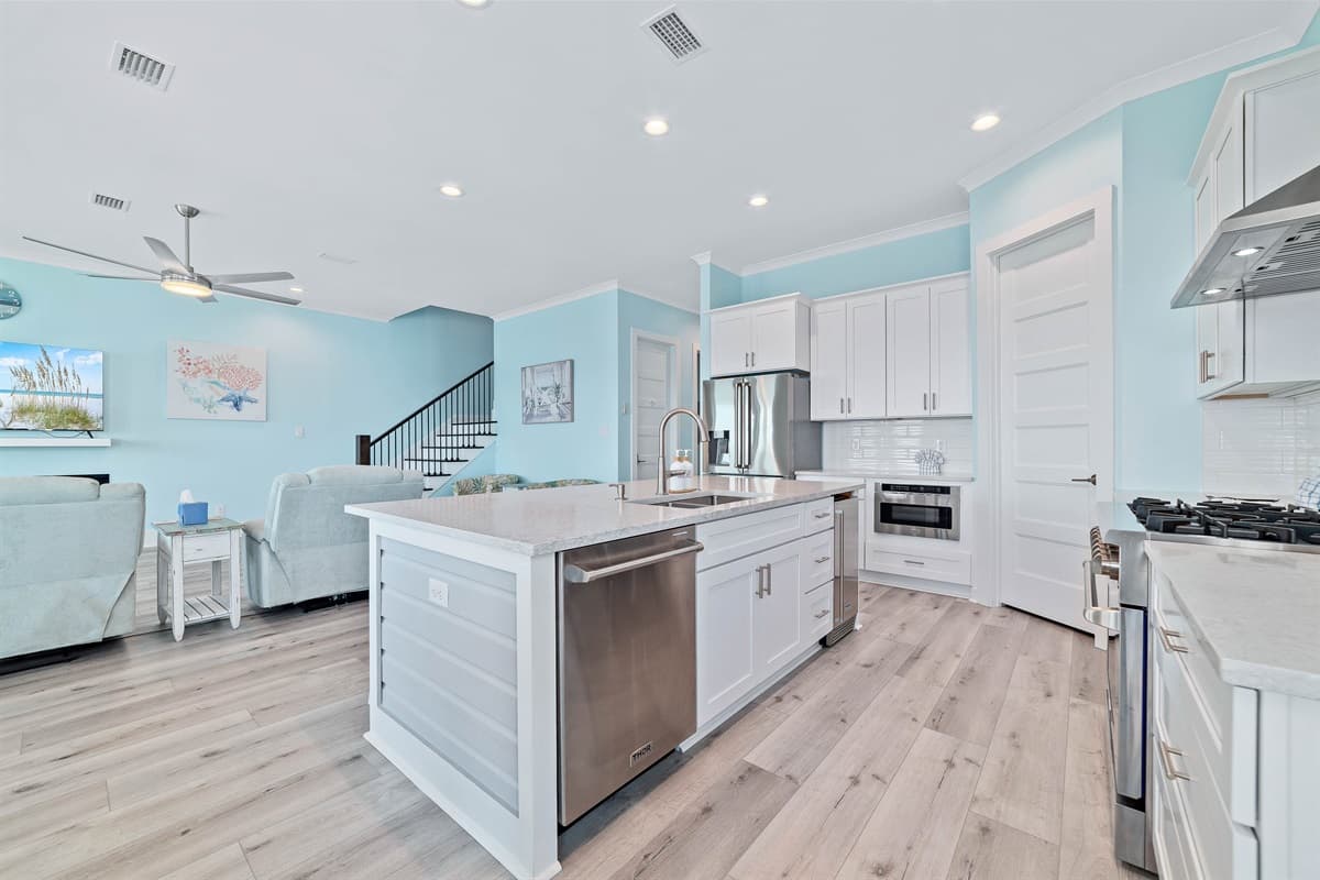 The modern kitchen features a large island with a sink and dishwasher, seamlessly connecting to the living area.