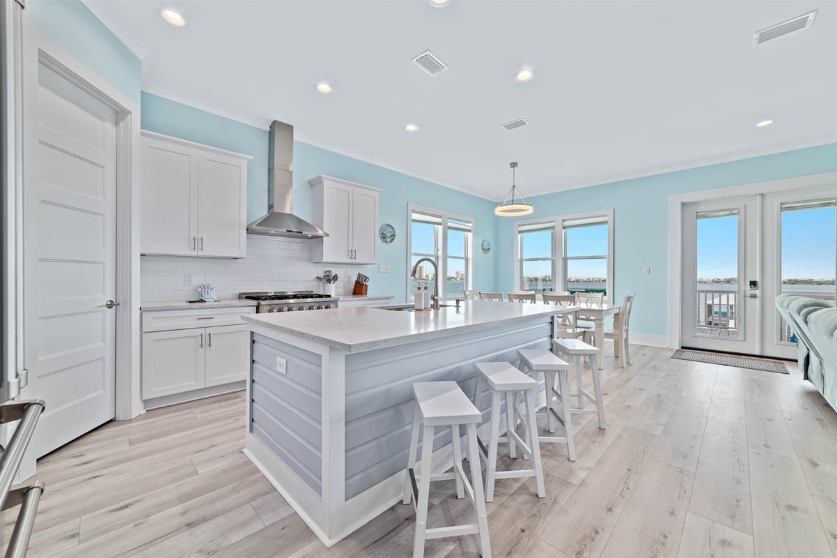 This bright and inviting main level seamlessly blends a modern kitchen, complete with a central island and bar seating, into a comfortable dining area. The open layout and abundant natural light create a welcoming atmosphere for cooking, dining, and social