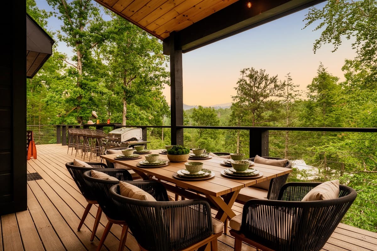 Enjoy memorable meals and breathtaking sunsets from this impressive outdoor dining space, complete with a long wooden table and comfortable seating for a crowd. The elevated deck provides panoramic views of the serene landscape, making it an ideal spot for