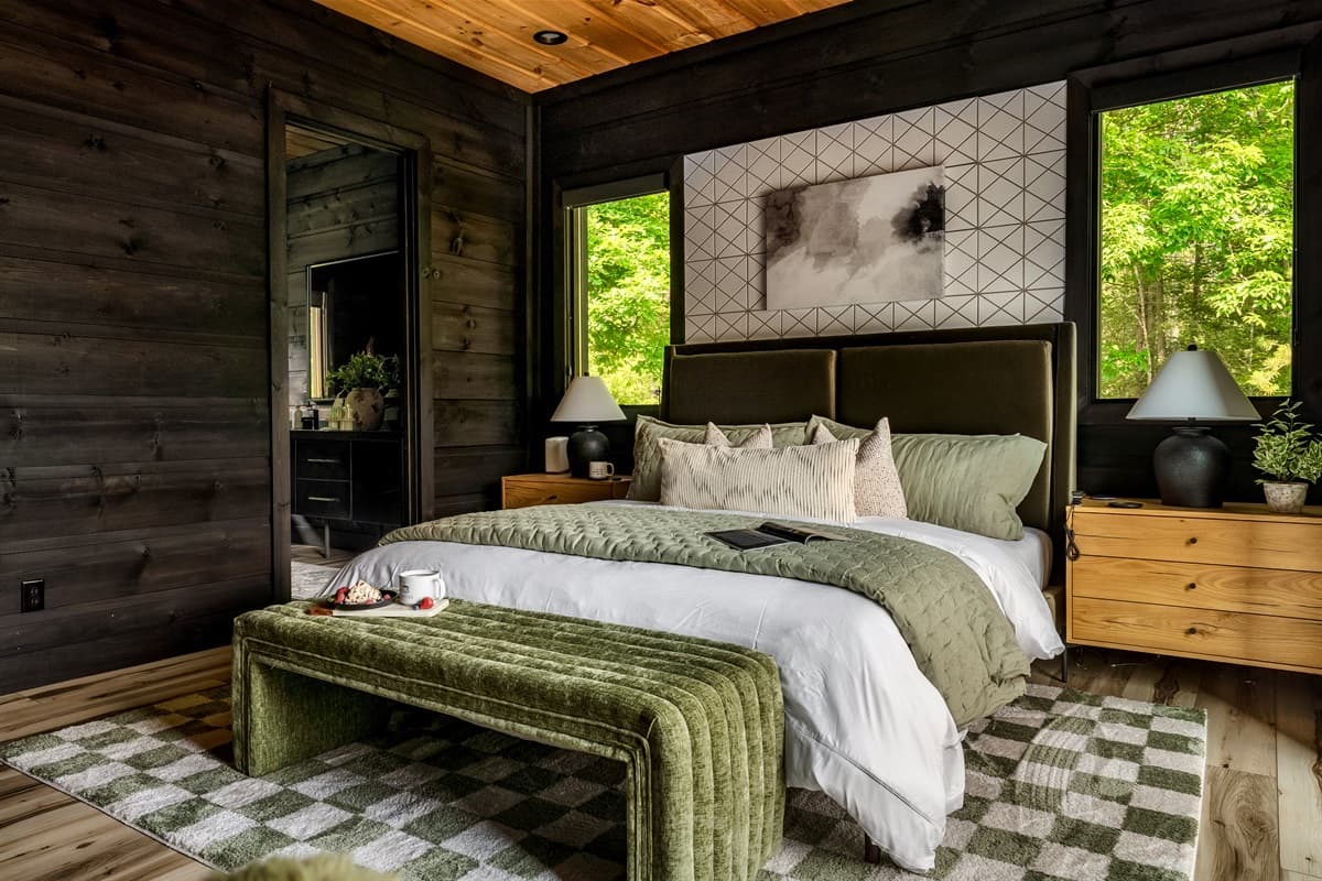 This inviting bedroom offers a luxurious retreat with a plush bed, ample pillows, and a striking patterned accent wall.