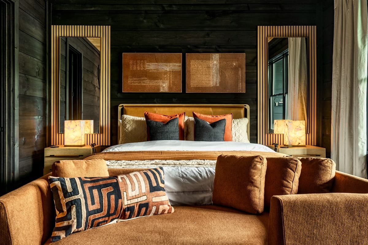This luxurious bedroom features a large, inviting bed with ample pillows, complemented by stylish accent mirrors and warm lighting.