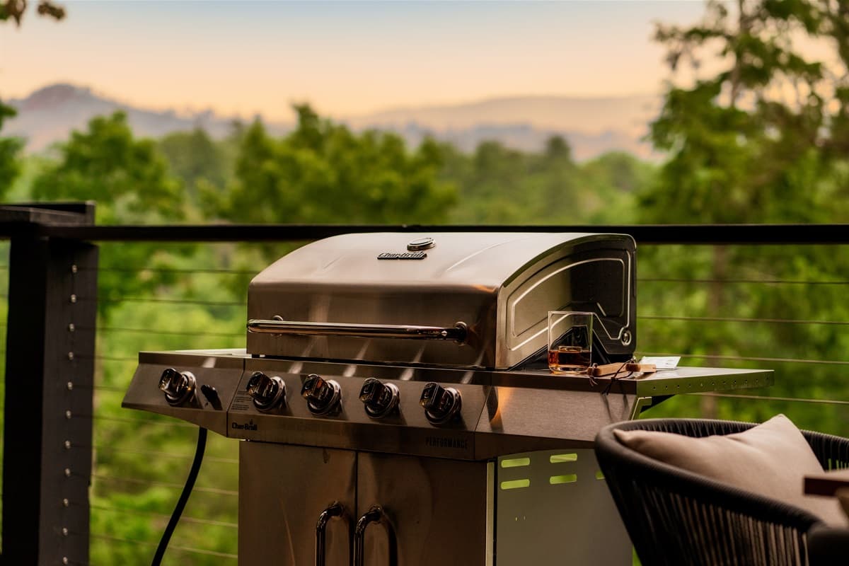 Enjoy al fresco cooking with this sleek outdoor grill, perfect for barbecues with a scenic view of the surrounding trees.