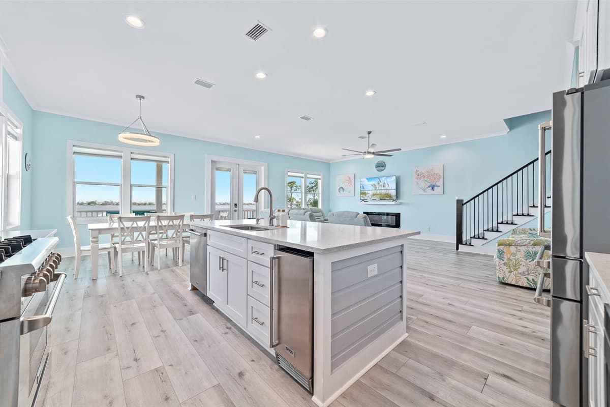 The expansive main living area features an open-concept kitchen with an island, a dining space, and a comfortable lounge area, all bathed in natural light.