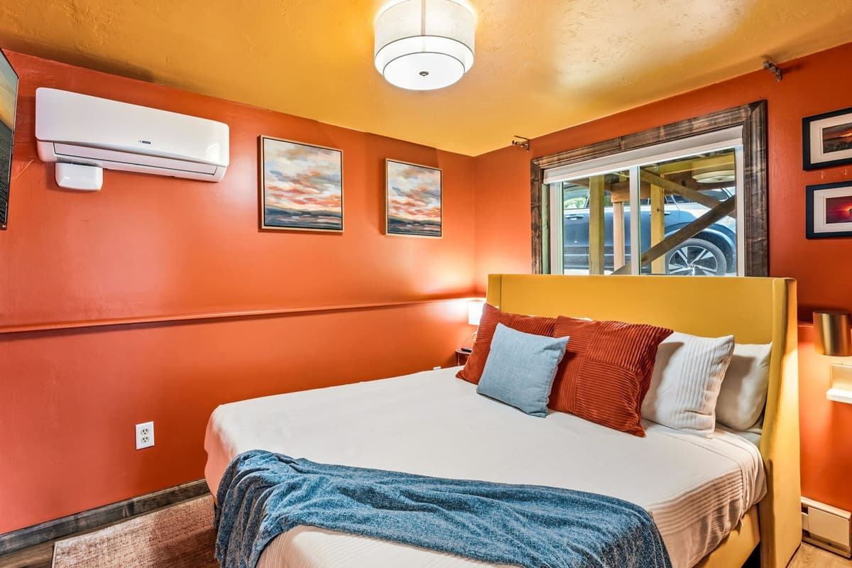 The Orange Room features a comfortable queen-size bed in a warm and inviting setting. The cozy atmosphere creates a relaxing retreat for a peaceful night's sleep.
