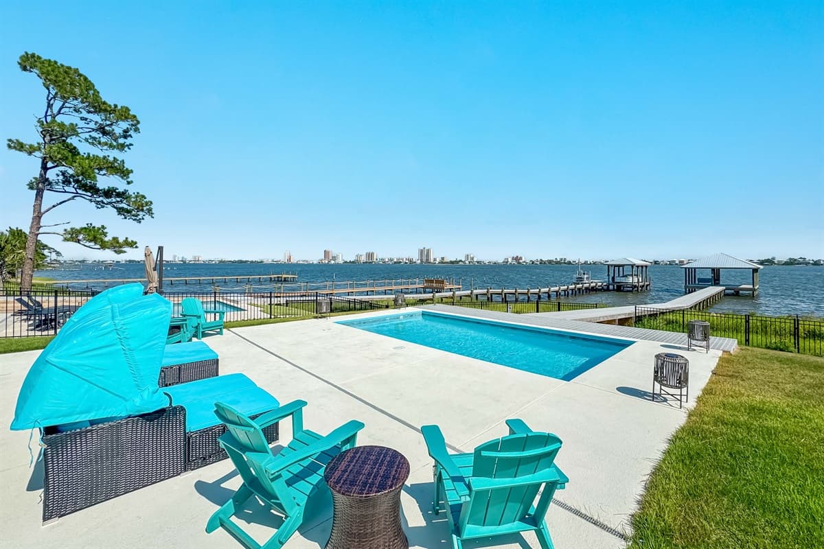 This stunning outdoor space features a private pool with ample lounge seating, overlooking a serene bay with private docks.