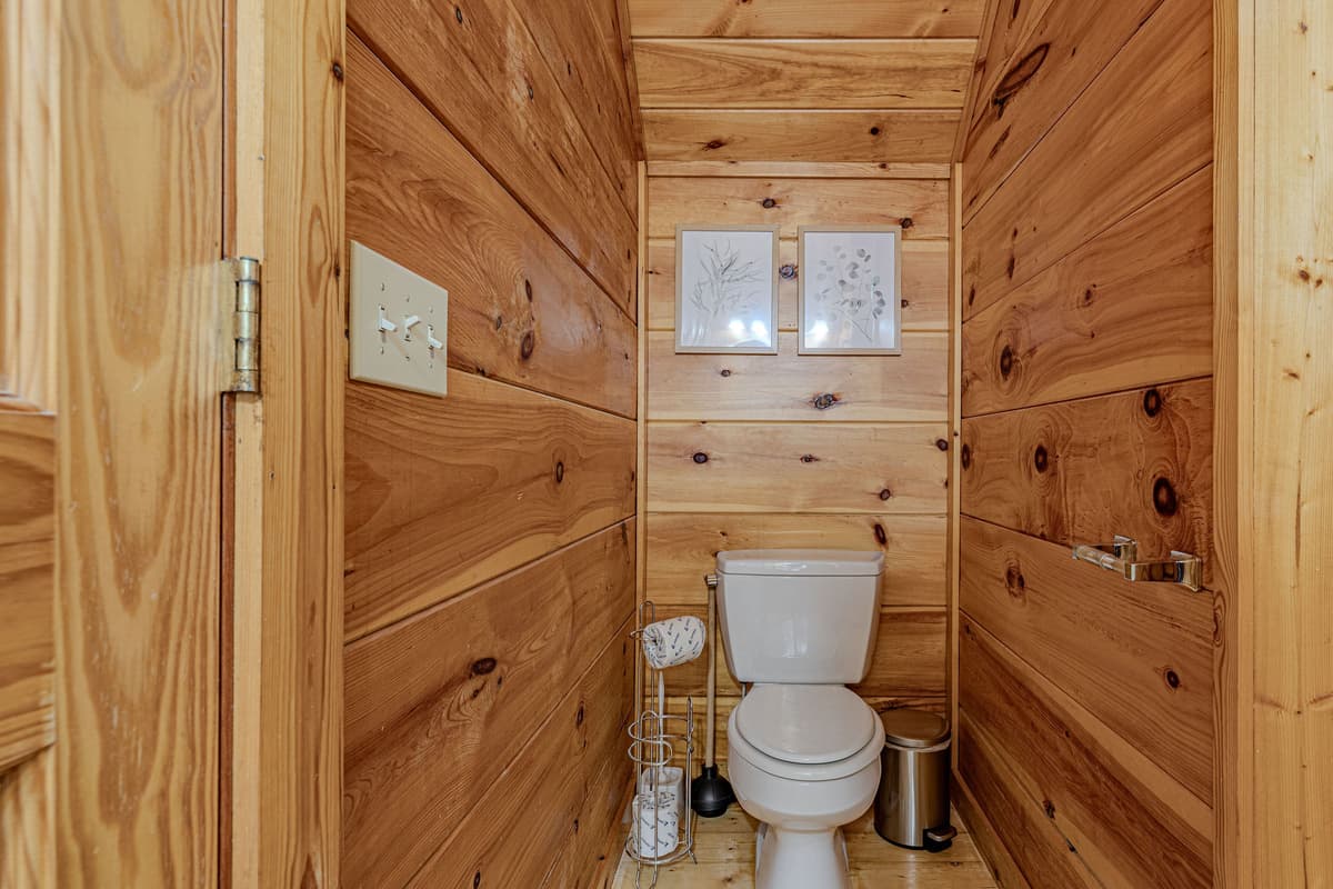 This convenient half-bathroom features warm wood paneling and essential amenities.