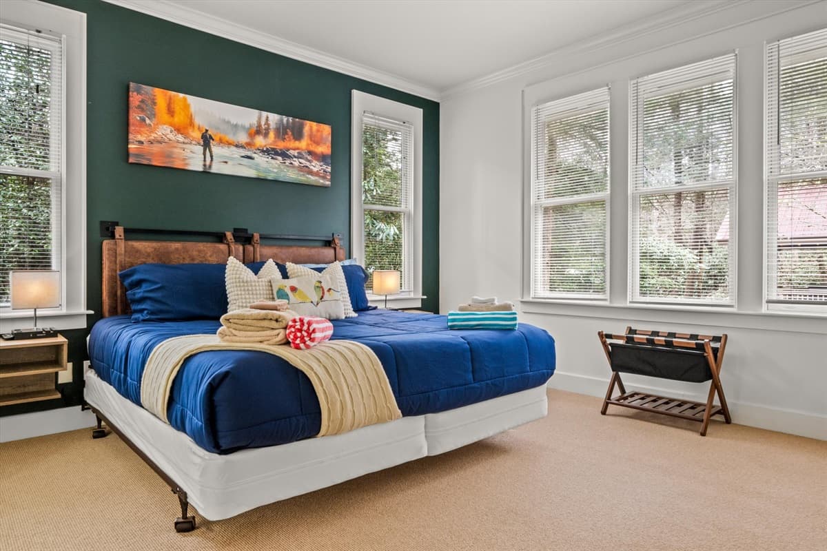 King Bedroom 1 with Blue Comforter, Wood Headboard, Green Accent Wall and Landscape Painting