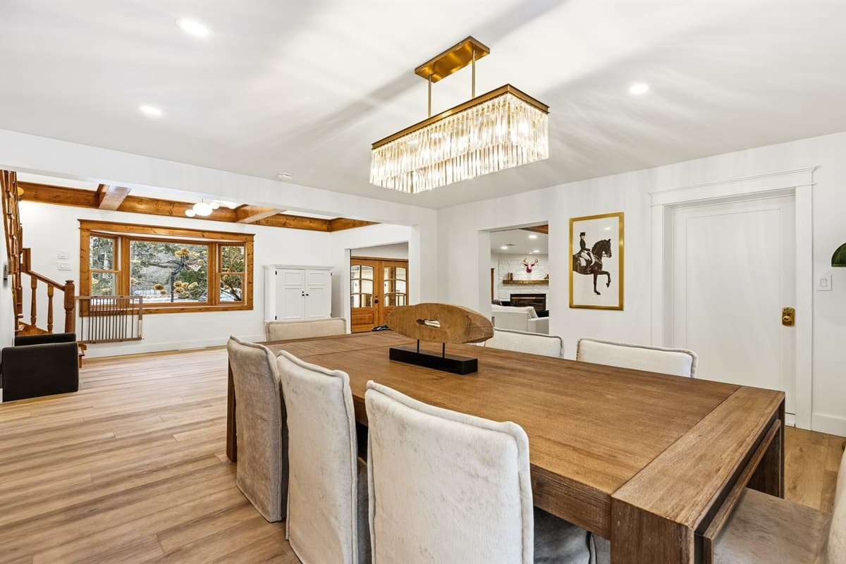 The dining table comfortably seats 8, with modern, rustic touches, the space is bathed in natural light from the large windows, creating a warm and inviting atmosphere.