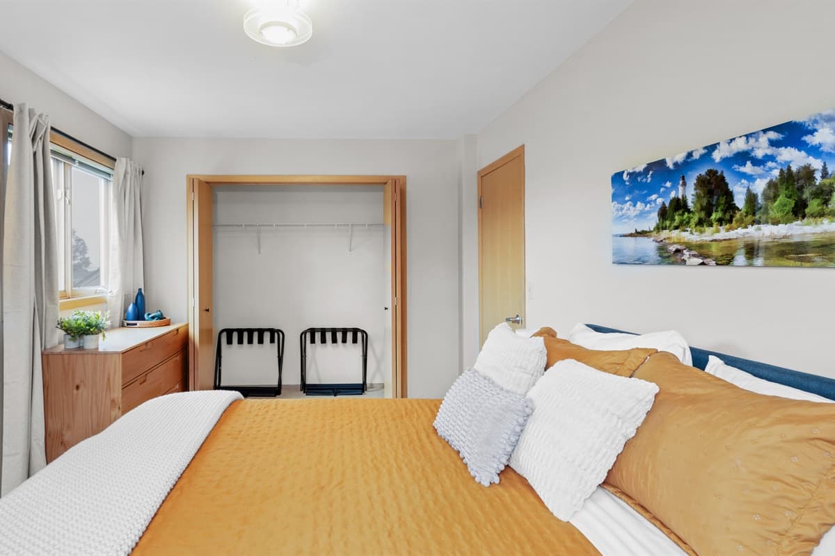 Step into this inviting queen bedroom, where natural light pours through large windows and soft, luxurious linens promise a peaceful night’s sleep.