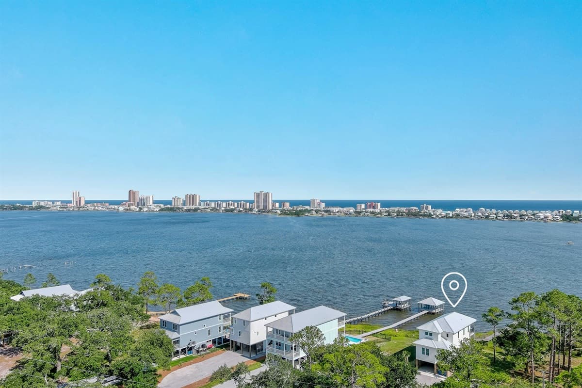 This stunning aerial view captures the vast expanse of the bay, with a distant city skyline and charming waterfront homes nestled along the serene coastline.