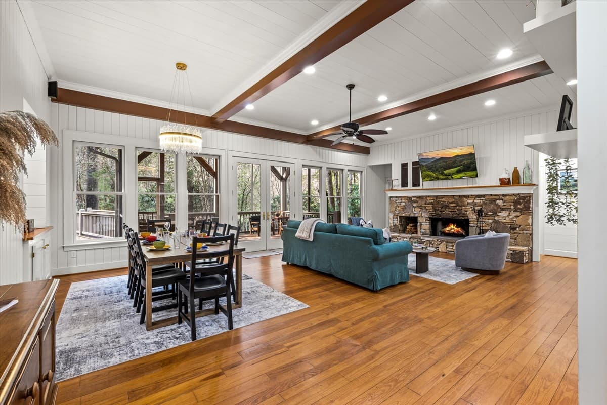 Open-Concept Living and Dining Area with Hardwood Floors, Stone Fireplace and Large Windows