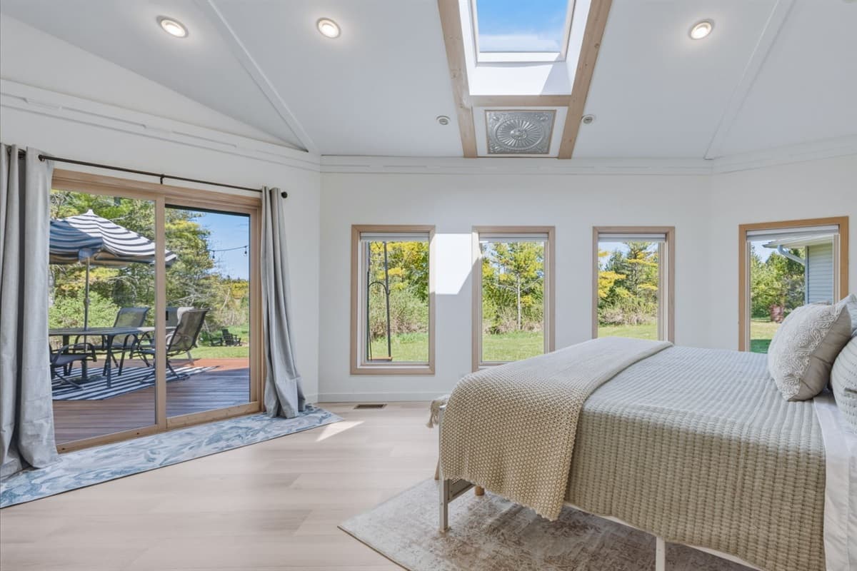 Spacious master suite featuring a comfortable king bed, large windows that bring in plenty of natural light, and a sliding glass door that opens directly to the outdoors.