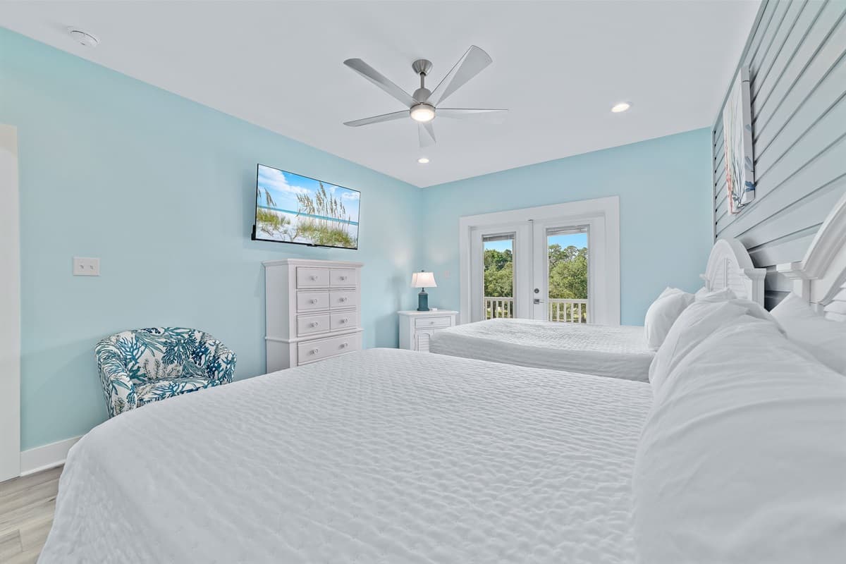 Ideal for flexible sleeping arrangements, this inviting bedroom offers two plush queen-sized beds, a convenient wall-mounted television, and a stylish dresser. French doors lead directly to a private outdoor deck, inviting in fresh air and views.