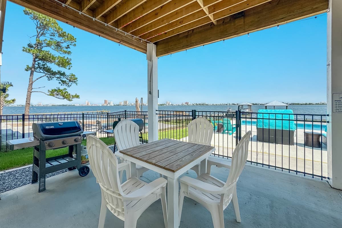 Enjoy al fresco dining and grilling on this spacious covered patio, complete with an outdoor dining table and a barbecue grill for preparing delicious meals. It's the perfect spot to relax and take in the serene water views and the adjacent turquoise pool