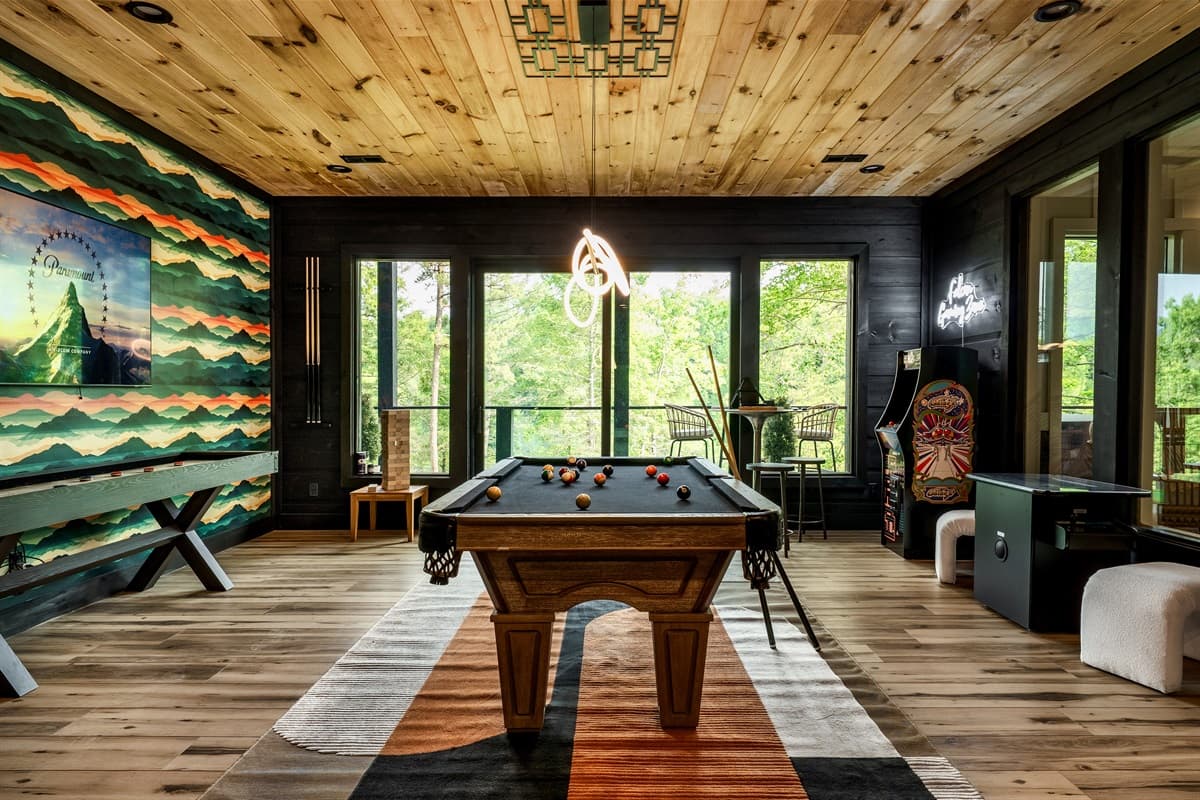 This ultimate game room features a full-sized billiard table, arcade machine, and a wall-mounted TV, all set within a vibrant and entertaining space.