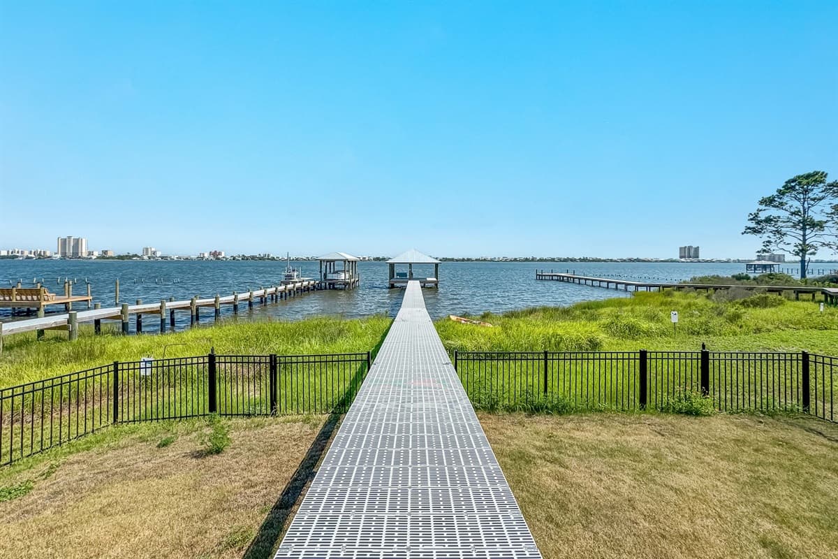 Enjoy direct access to the water from this impressive property, boasting a long, sturdy walkway that extends to a private covered dock, perfect for fishing or relaxing. The expansive views of the tranquil bay and the distant city lights create a serene and