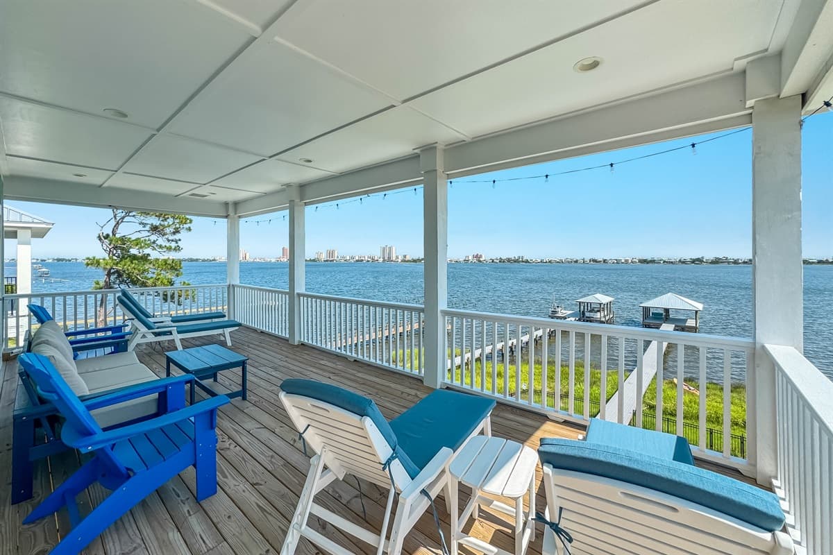 This expansive covered deck offers stunning waterfront views, comfortable lounge chairs, and ample seating for enjoying the outdoors.