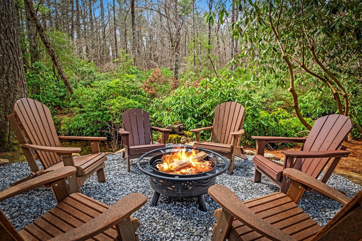 Fire Pit Directly on the River, Lit Up at Night with Adirondack Chairs Ready for Roasting S'mores