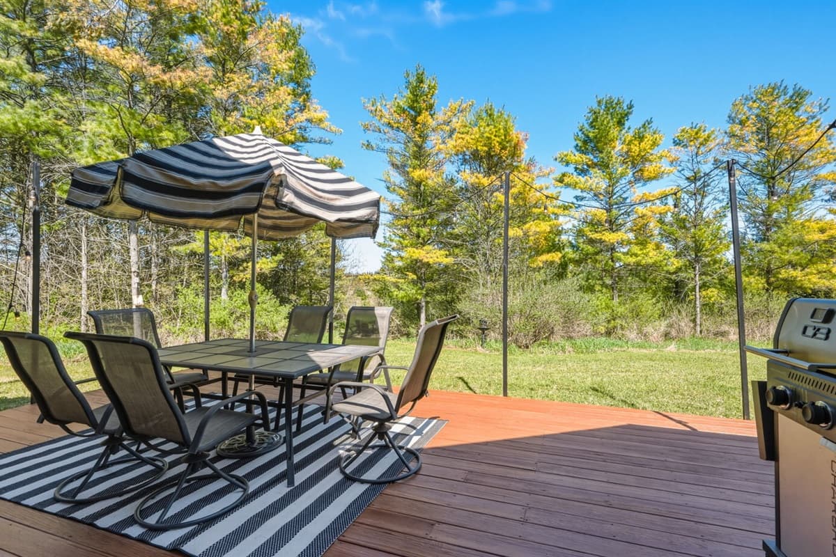 Outdoor patio designed for relaxing and entertaining, featuring a dining table with umbrella for shaded meals, comfortable seating, and a propane grill for easy outdoor cooking.