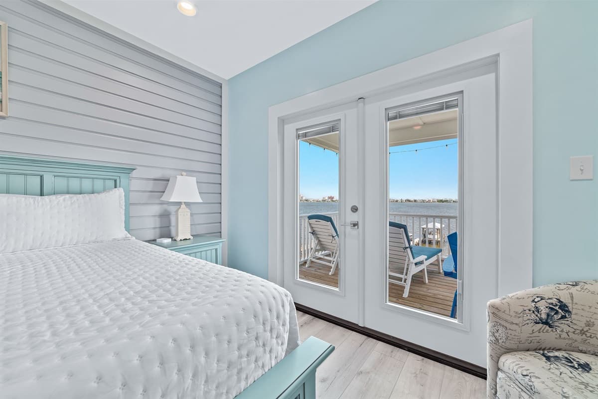 This bright bedroom features a comfortable king-sized bed with a calming shiplap accent wall, and direct access to an outdoor deck.
