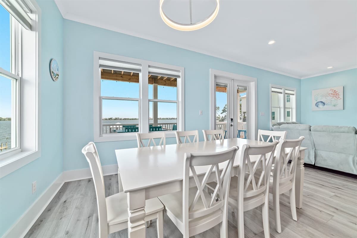 Enjoy memorable meals in this bright and airy dining room, featuring a large table with seating for eight and direct access to an outdoor balcony. The room is designed for comfortable gatherings, with picturesque views of the serene water visible through m