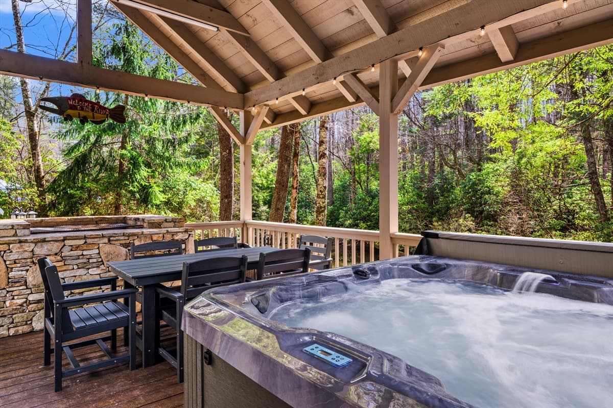 Bubbling Hot Tub and Outdoor Dining Table on the Covered Deck with String Lights and Stone Charcoal Grill (guests bring own charcoal)