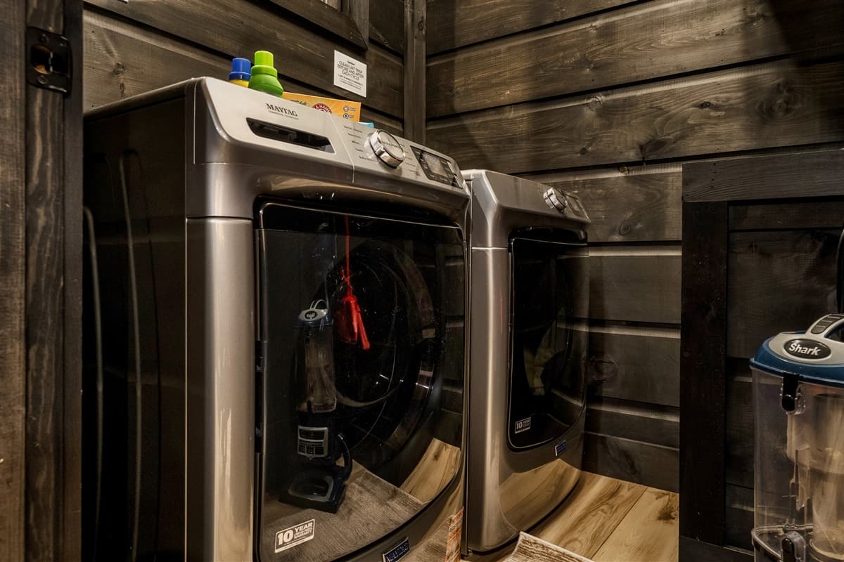This convenient laundry area features a modern washer and dryer, set against stylish dark wooden walls.