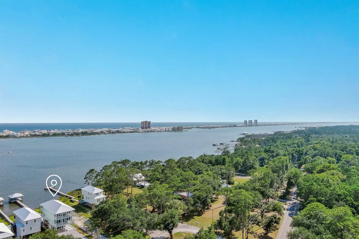 Witness the breathtaking beauty of this coastal region from above, where the serene bay waters transition into the vast expanse of the Gulf. The horizon showcases a vibrant city skyline, all framed by miles of pristine green coastline.