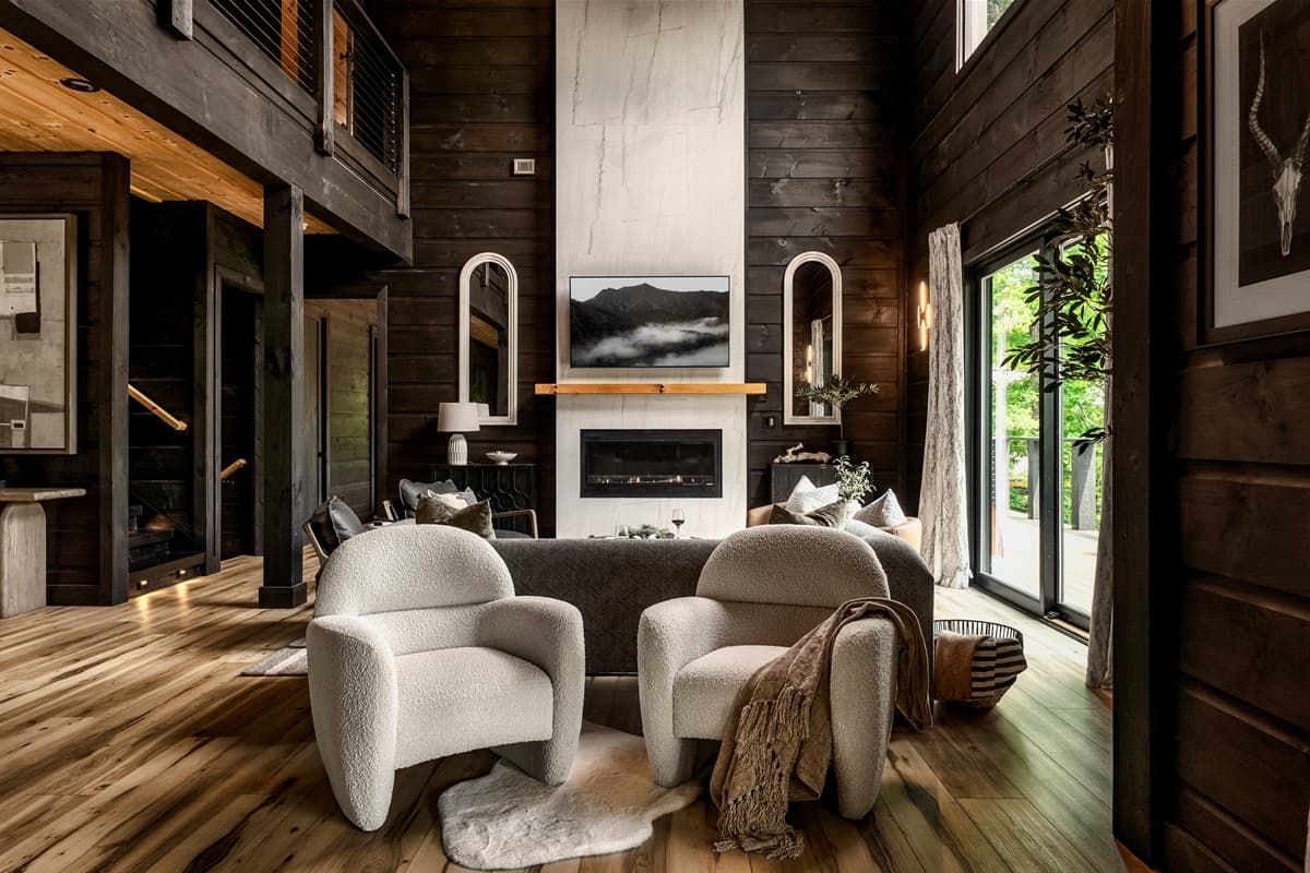 Relax in comfort in this beautifully designed living space, offering soft, light-colored seating that contrasts stylishly with the rich, dark wood accents and a sleek fireplace. The contemporary decor and warm lighting make it an ideal spot for unwinding a