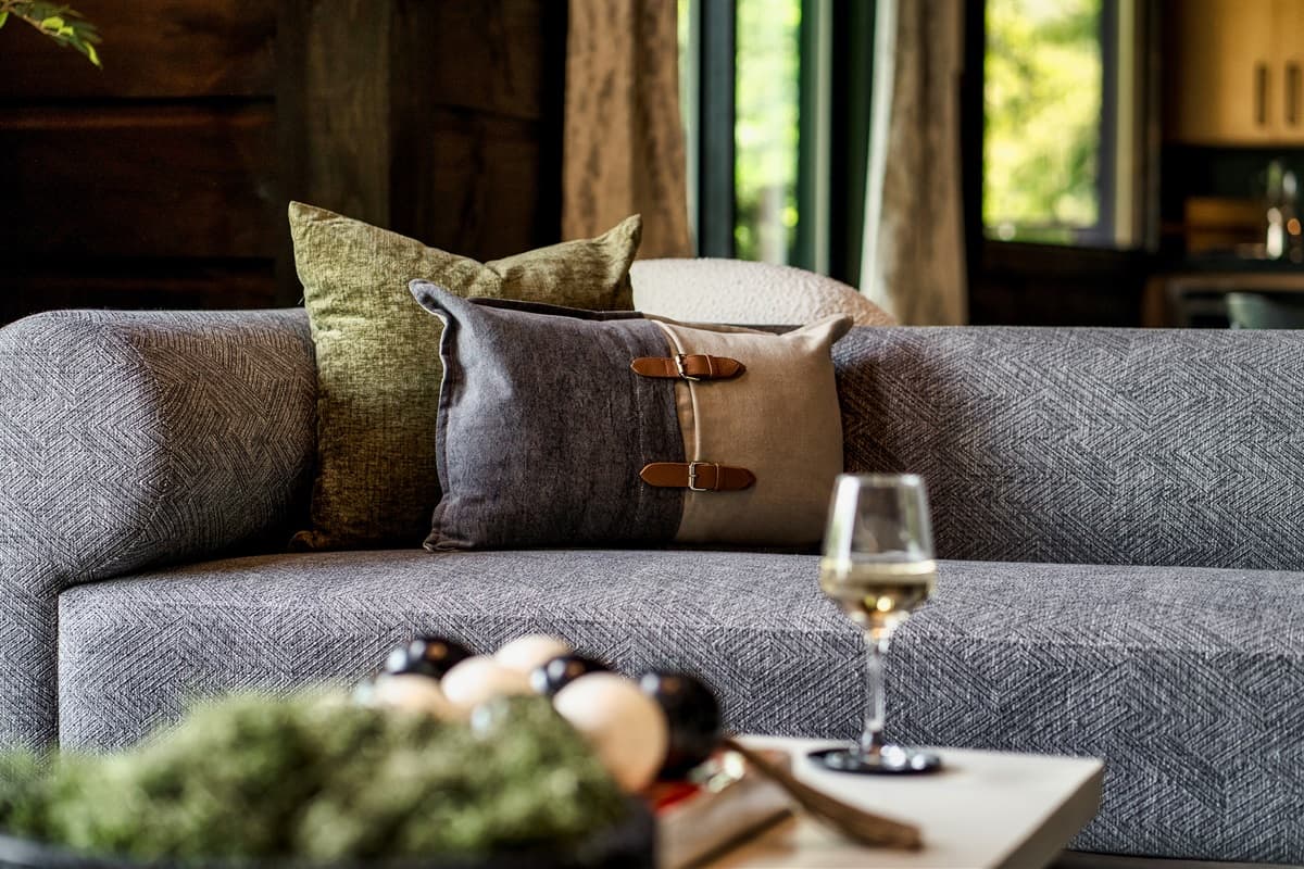 Relax on the plush sofa, adorned with stylish decorative pillows and a cozy throw, perfect for unwinding with a glass of wine.