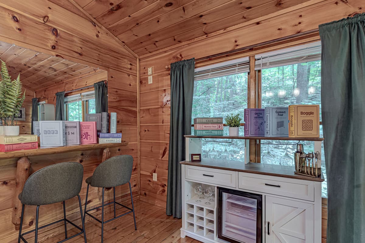 Discover a cozy reading and bar nook, featuring a mini-fridge, comfortable stools, and charming decor with a mirrored backdrop.