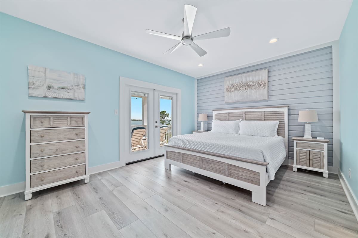 This spacious bedroom features a comfortable king-sized bed, a rustic-style dresser, and direct access to an outdoor deck.