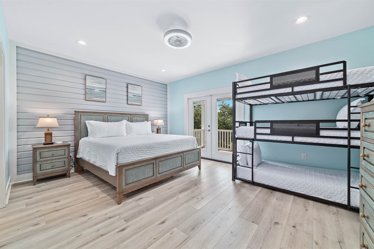 This versatile bedroom features a comfortable king-sized bed, a twin-over-full bunk bed, and direct access to an outdoor deck.