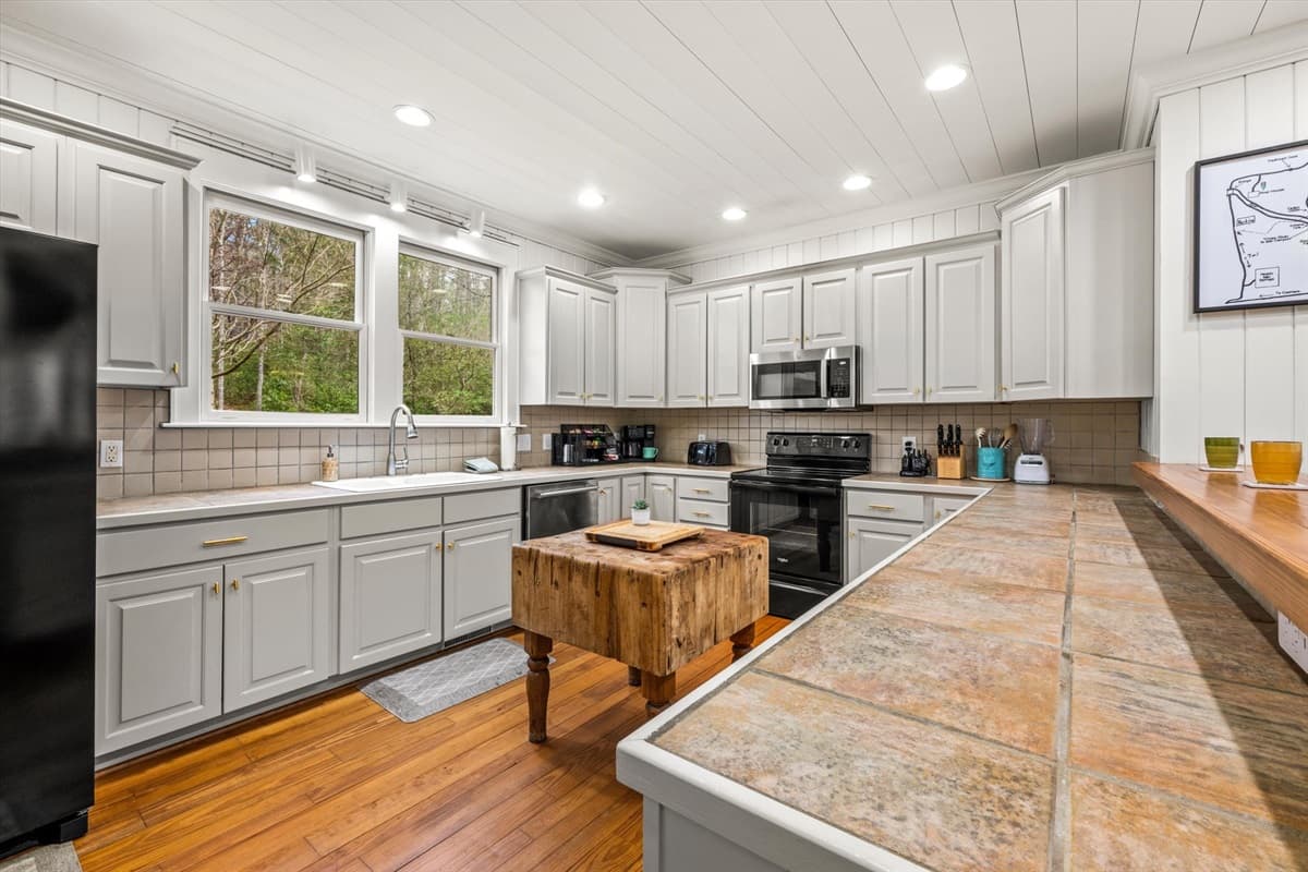 Full Kitchen View with Gray Cabinets, Granite Countertops and Butcher Block Island. Walkie talkies are provided on the kitchen counter, with limited range but often able to reach between the house and parts of the nearby trail.