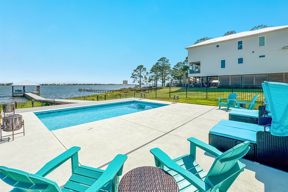 This stunning outdoor oasis features a private pool with ample lounge seating, offering expansive views of the bay and private docks.