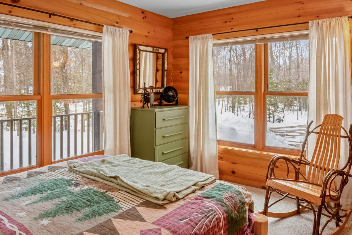 Settle into the comfortable main-level queen bedroom, featuring a cozy bed and large windows that bring in plenty of natural light.