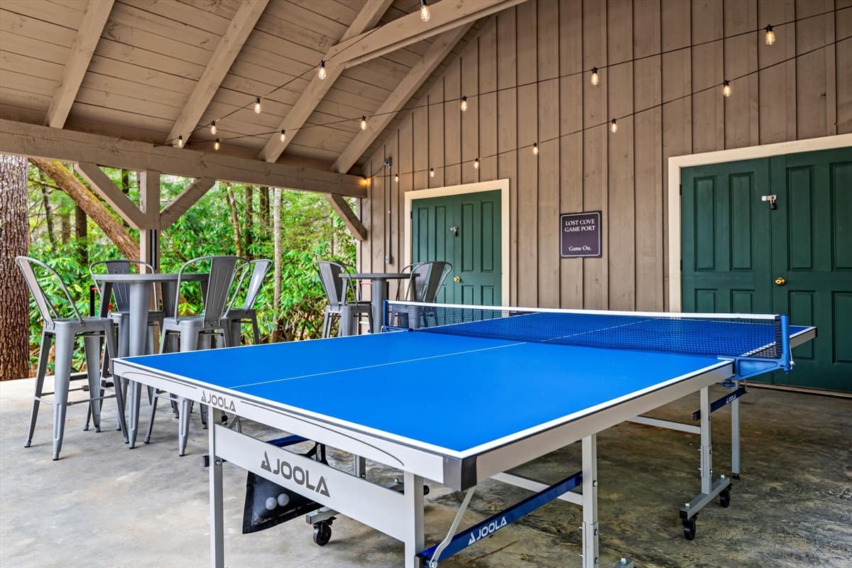 JOOLA Ping Pong Table and Outdoor Jenga in the Covered Game Area with Bar Seating and String Lights