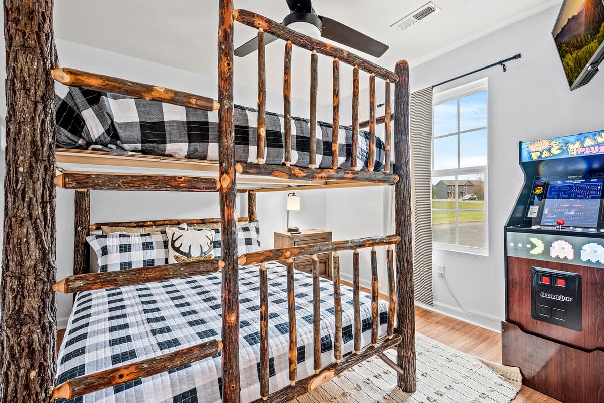 This queen-over-queen bunk bedroom offers comfortable sleeping space for everyone, while the arcade machine adds an extra dose of entertainment.
