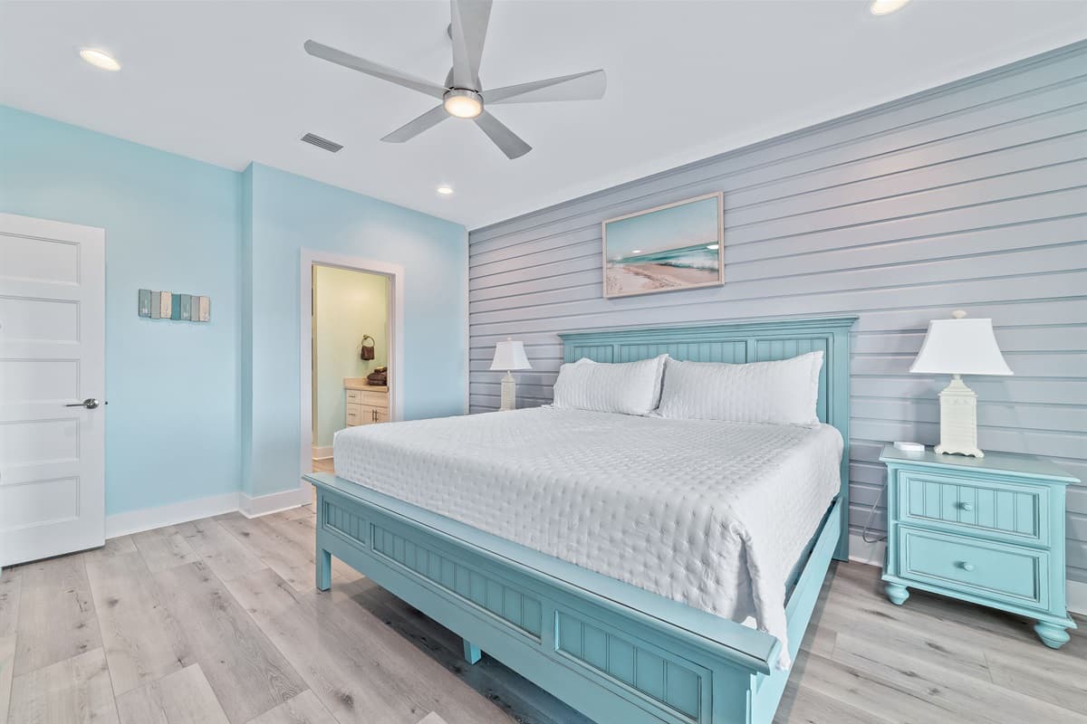 This bright bedroom features a comfortable king-sized bed, a soothing blue shiplap accent wall, and direct access to an en-suite bathroom.