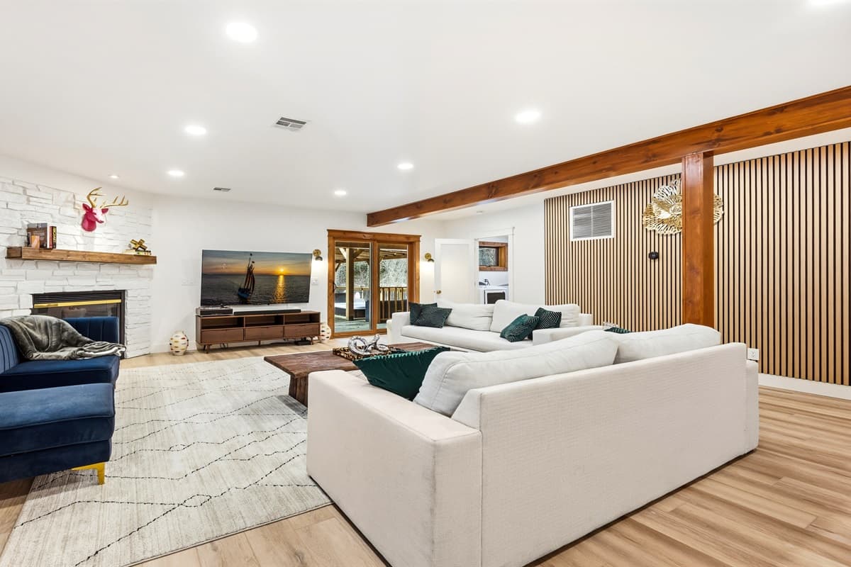 The living room boasts plush seating, velvet accent chairs, a stunning white stone fireplace, and a large smart TV—ideal for cozy nights in.