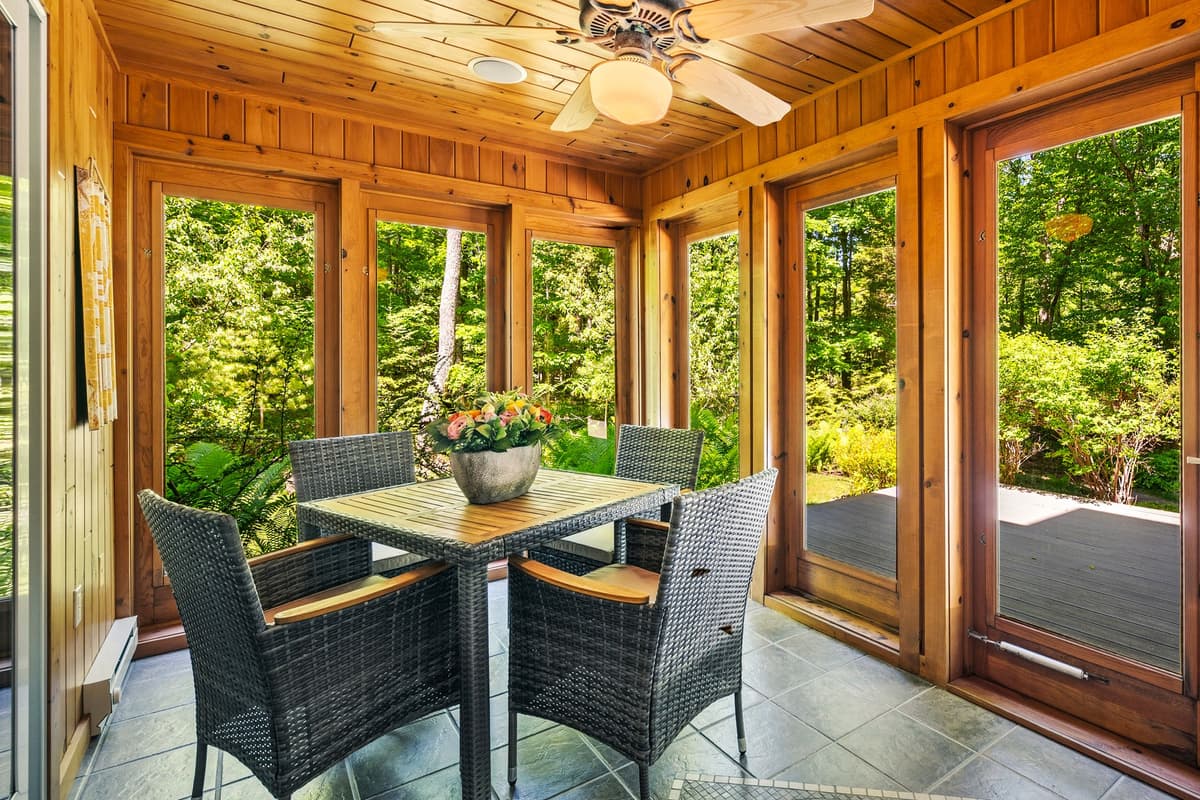 Bright and welcoming sunroom featuring a table and comfortable seating, perfect for enjoying coffee, meals, or relaxing with a good book.