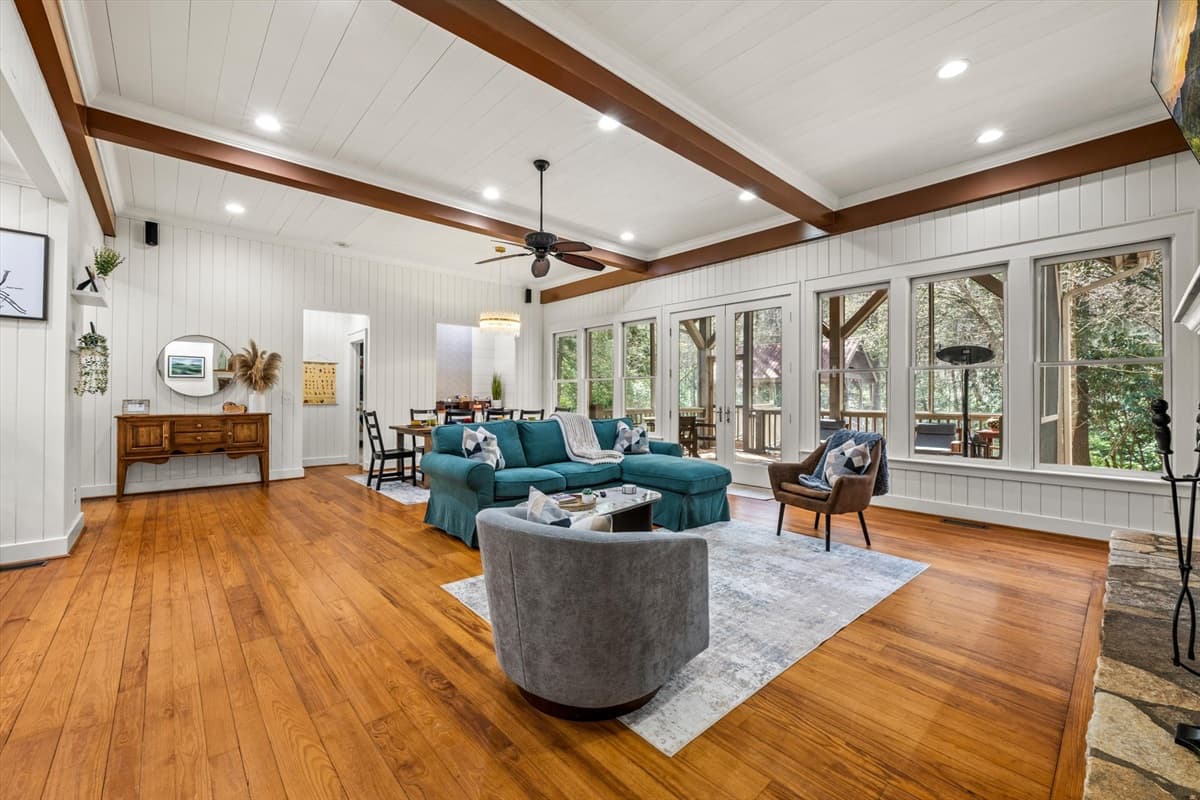 Wide-Angle Living Area with Exposed Beams, Shiplap Walls, Large Windows and Porch View