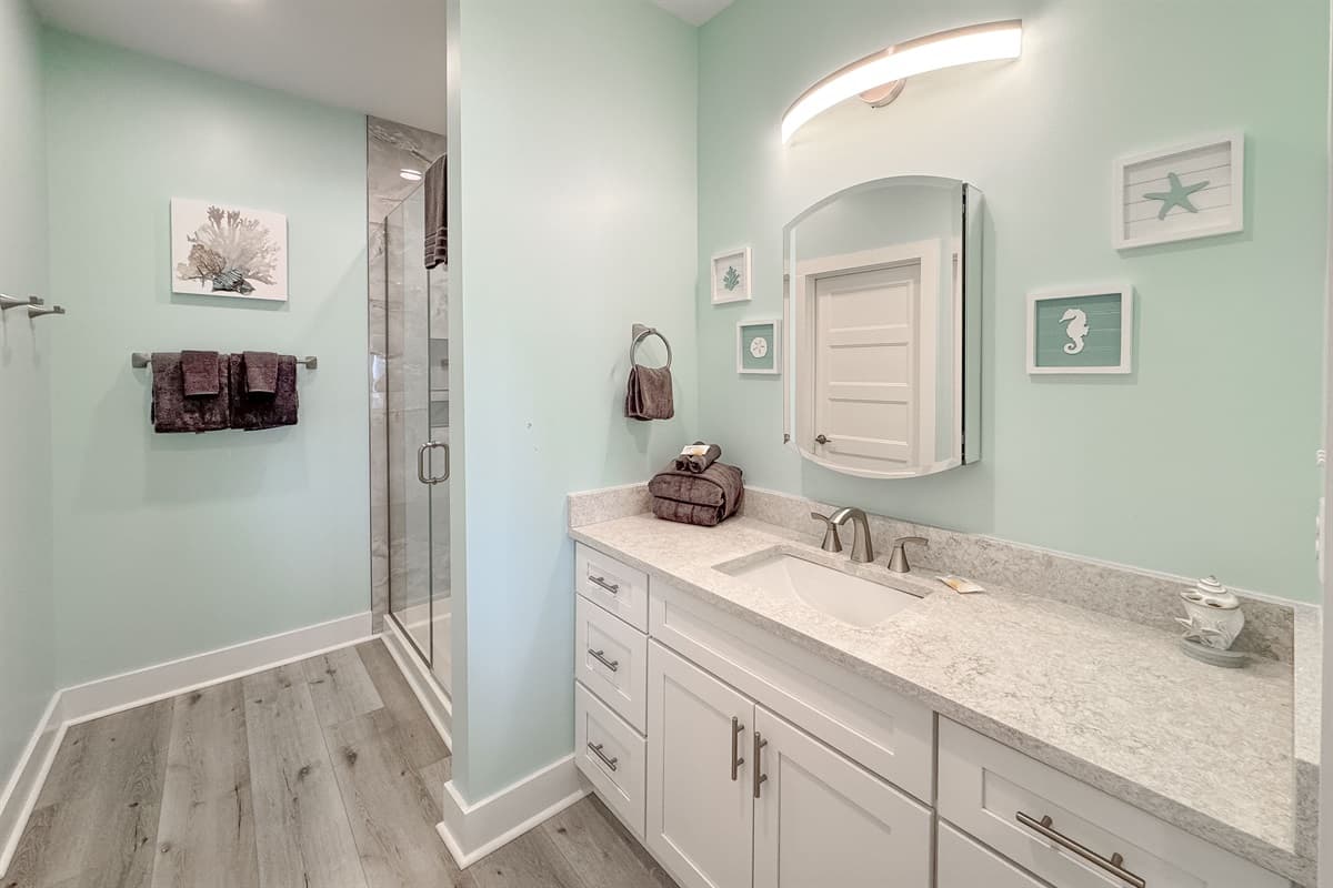 This modern bathroom features a sleek vanity with a single sink, a large mirror, and a spacious walk-in shower.