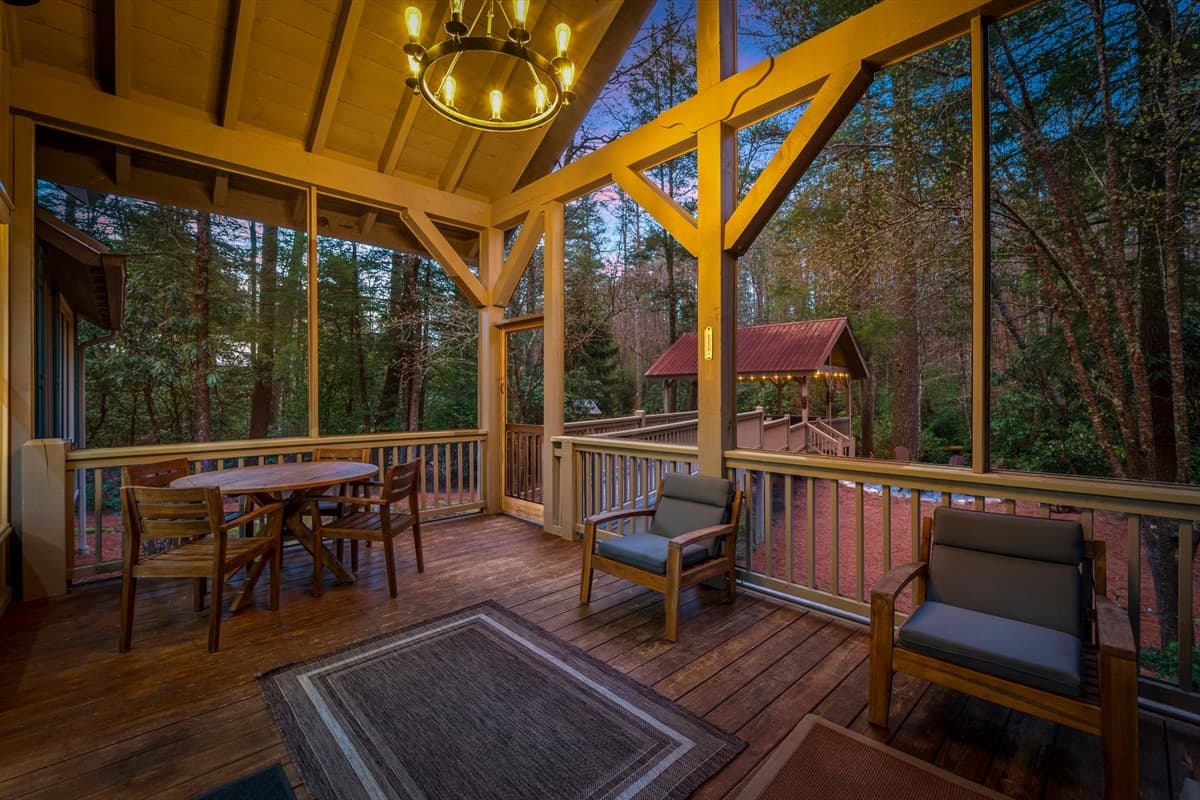 Covered Porch with Dining Table, Lounge Seating and Chandelier Under Exposed Wood Beams