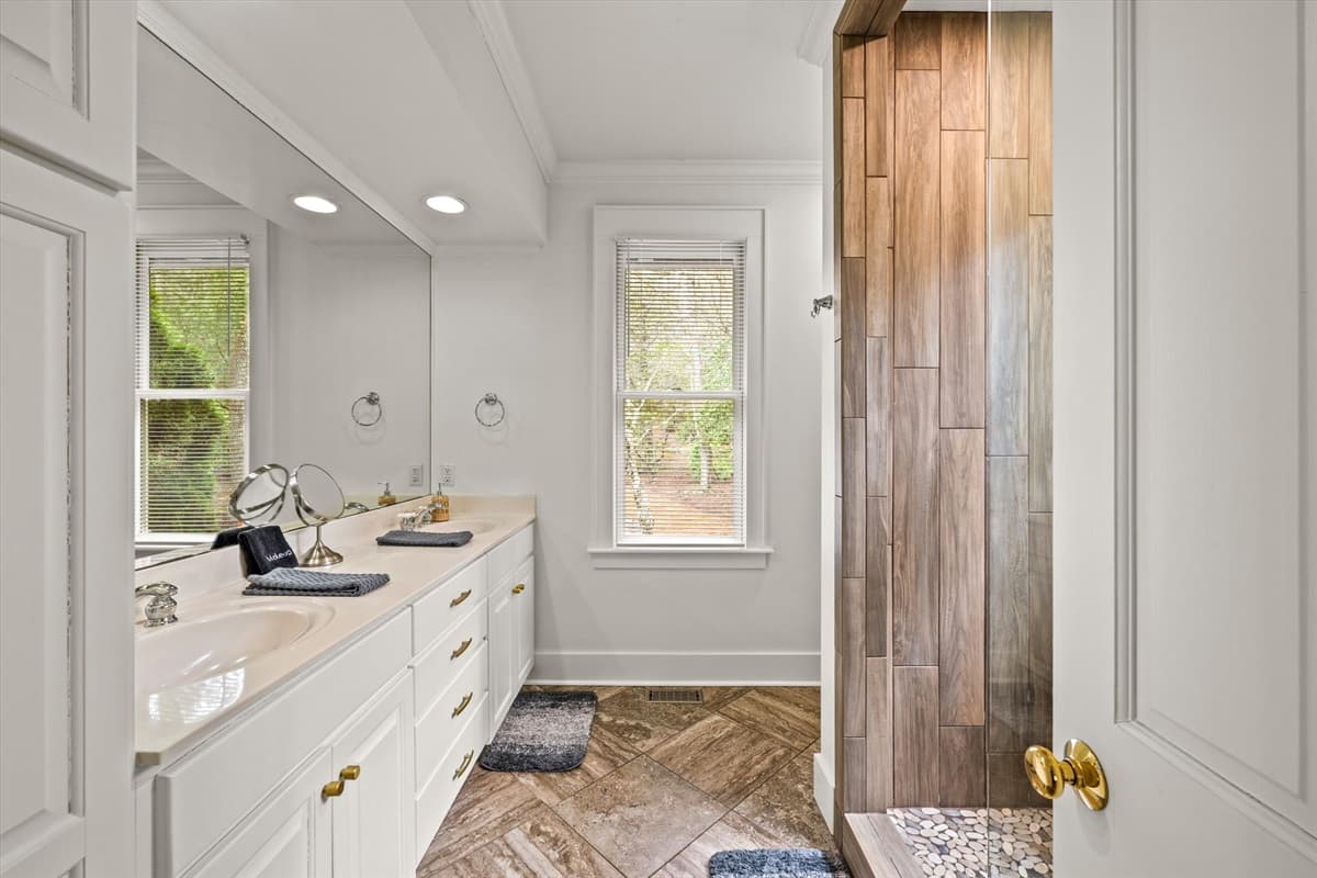 Ensuite Bathroom with Double Vanity, Herringbone Tile Floor and Wood-Accented Shower Door
