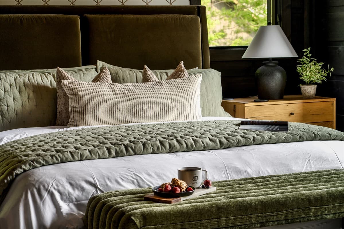 This luxurious bed, adorned with soft pillows and a cozy green blanket, offers a perfect retreat for relaxation with a tray ready for a snack or drink.
